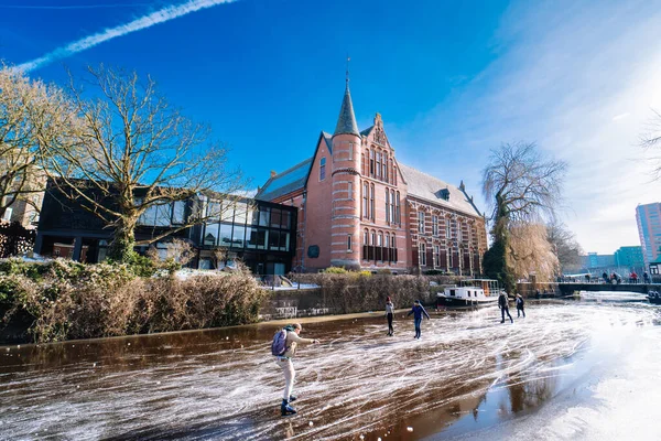 Personas patinando sobre hielo en el canal congelado en el centro de la ciudad en Holanda. Pueblos haciendo fotos, caminando y patinando en el canal congelado en invierno. Diversión de invierno en la ciudadGroninga. Países Bajos. 14.02.2021. — Foto de Stock