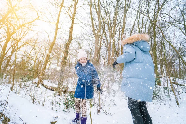 Enfants jouant sur la neige en hiver. Joyeux rire les enfants dans la belle forêt enneigée d'hiver le jour de Noël. Bonne enfance, concept actif de vacances d'hiver. — Photo