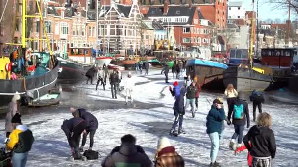 사람들은 네덜란드의 도심에 있는 얼어붙은 운하에서 아이스 스케이팅을 한다. 겨울에 얼어붙은 운하에서 그림을 그리고 걷고 스케이트를 타는 사람들. 겨울에는 서울에서 즐겁게 보낸다. 네덜란드. 14.02.2021. — 비디오