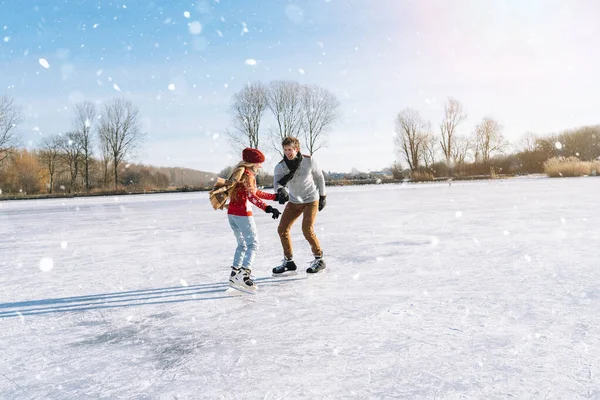 Loving couple in warm sweaters having fun on ice. Woman and man ice skating outdoors in sunny snowy day. Active date on ice arena in winter Christmas Eve. Romantic activities and lifestyle concept.