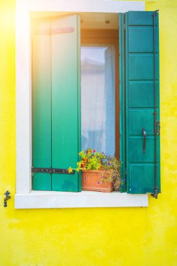 İtalya 'daki Venedik gölünde tipik bir turist adası. Güzel su kanalları ve renkli mimari. Pencereli ve panjurlu renkli bir duvar. Burano adasında mimari.