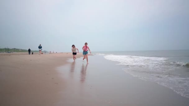 Hermosas chicas jugando en la playa tropical. A los niños les gusta el mar caliente. Los niños se divierten y saltan en el agua de mar en las olas en un día cálido y soleado en la orilla del mar. Viajes de verano y concepto de vacaciones — Vídeos de Stock