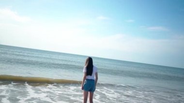 Beautiful girls playing at tropical beach. Kids enjoying warm splashing sea. Children having fun and jumping in sea water on waves on warm sunny day on seashore. Summer travel and vacation concept.