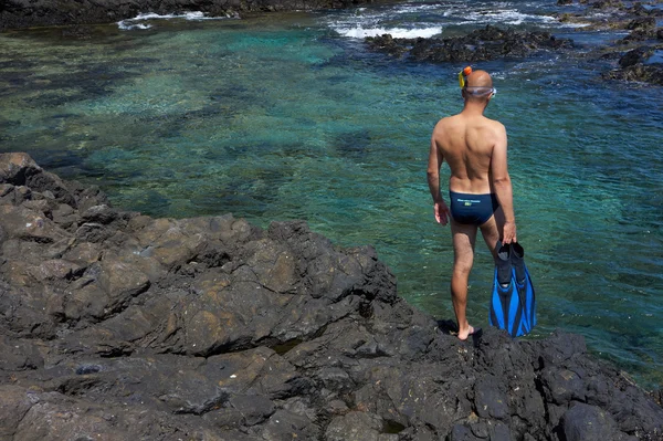 Joven con equipo de snorkel en la costa rocosa — Foto de Stock