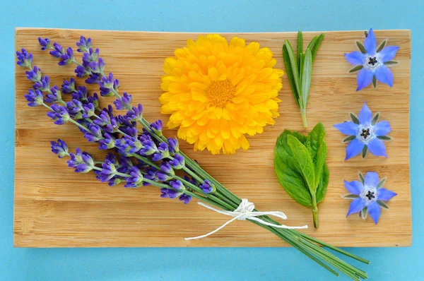 Summer herbs and edible flowers on wooden plate. — Stock Photo, Image