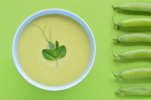 Cold creamy green pea soup and pea pod.