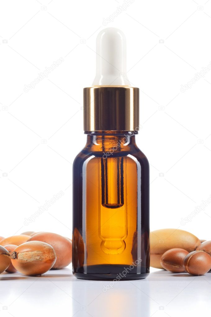 Argan oil and argan nuts on white background.