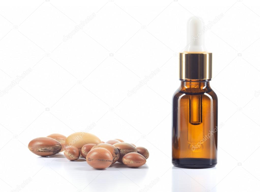 Argan oil and argan nuts on white background.
