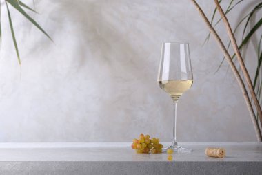 Taş bir masada bir bardak beyaz şarap, bir mantar ve bir demet üzüm. Hafif arkaplan.