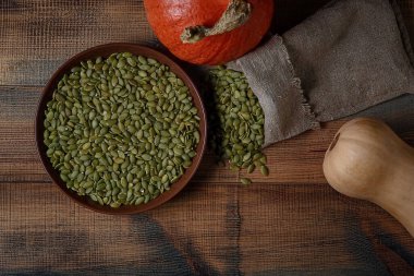 Tahta bir masanın üzerinde balkabağı ve kabağı tohumları. Üst görünüm.