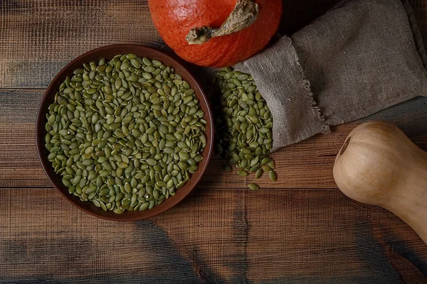 Tahta bir masanın üzerinde balkabağı ve kabağı tohumları. Üst görünüm.