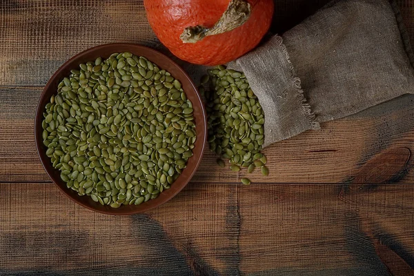 Tahta bir masanın üzerinde balkabağı ve kabağı tohumları. Üst görünüm.