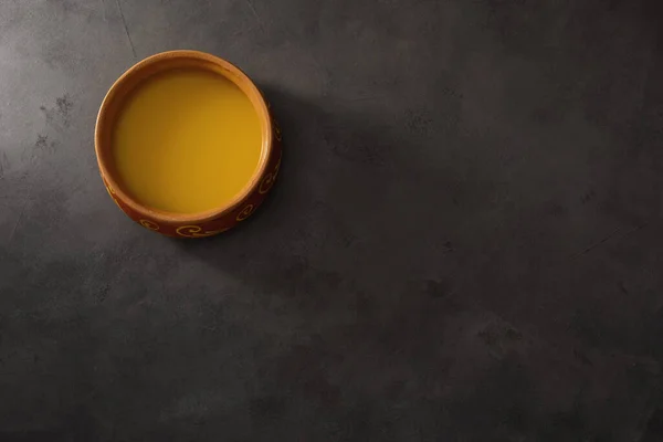 Saf OR Desi Ghee aynı zamanda sıvı tereyağı olarak da bilinir. Saf OR Desi Ghee seramik kaselerde eski ahşap bir masada. Üst görünüm.