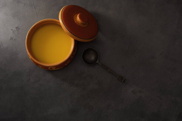 Pure OR Desi Ghee also known as clarified liquid butter. Pure OR Desi Ghee in ceramic bowls on an old wooden table. Top view.