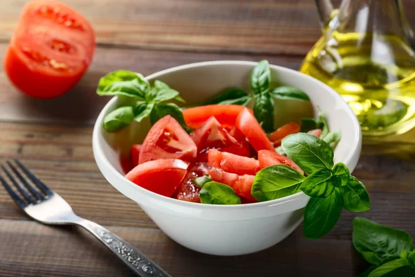 토마토는 식탁에 허브와 올리브유를 세라믹 접시에 놓는다 스톡 이미지