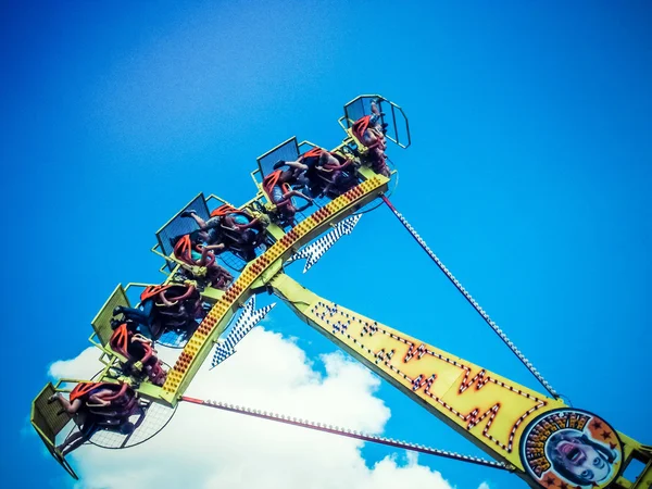 People ride on a huge attraction on the background of blue sky — Stock Photo, Image