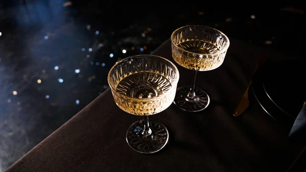 Servis masasının karanlık arka planında iki popüler klasik şampanya kadehi. — Stok fotoğraf