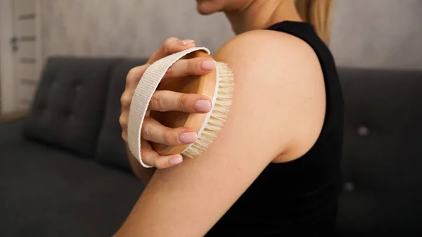 Jovem usa uma escova seca para auto-massagear os braços e ombros — Fotografia de Stock