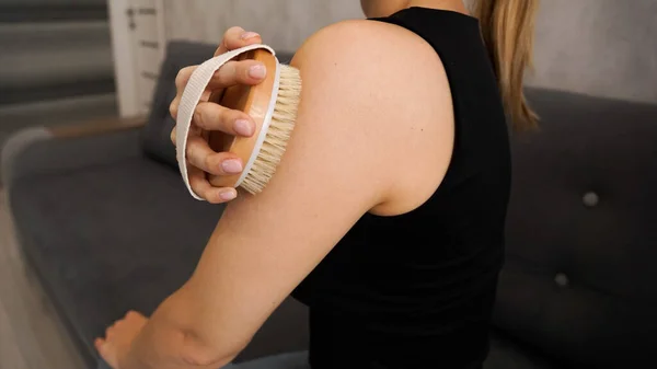 若い女性は自分の腕や肩をマッサージするために乾燥ブラシを使用します — ストック写真