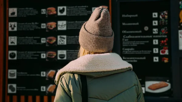 Donna in una strada urbana food court sceglie il cibo da un menu — Foto Stock