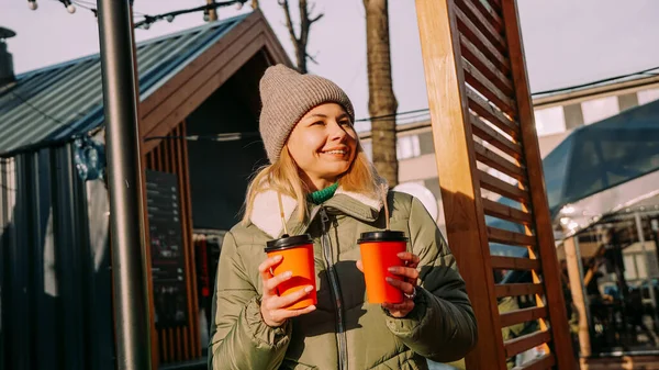 Mujer lleva dos tazas de café o vino caliente en la ciudad fuera del patio de comidas —  Fotos de Stock
