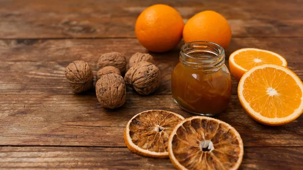Солодке апельсинове варення або мармеладний десерт з волоськими горіхами на дерев'яному фоні — стокове фото