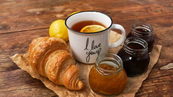 Thé au citron, confiture maison, croissant sur table en bois. Concept petit déjeuner. — Photo