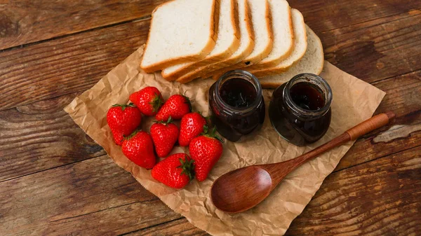 Rebanadas de pan y delicioso frasco de mermelada de fresa y bayas frescas en madera —  Fotos de Stock