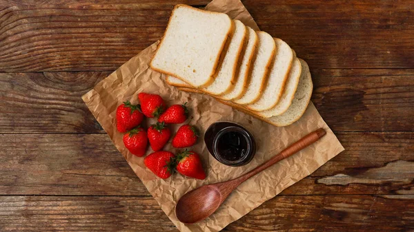 Rebanadas de pan y delicioso frasco de mermelada de fresa y bayas frescas en madera —  Fotos de Stock