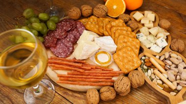 Şarap için atıştırmalık. Peynir ve et tabağı. Sosis, peynir, fındık, üzüm, tahta masada kraker. Romantik randevu ya da arkadaşlarla buluşma için İtalyan yemekleri