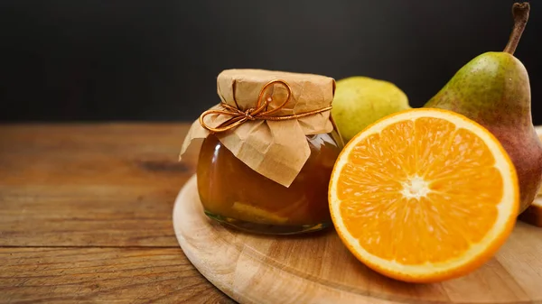 玻璃瓶的自制梨子和橙子果酱与新鲜的水果在木制桌子上 自制的橘子酱 放在玻璃瓶里 — 图库照片