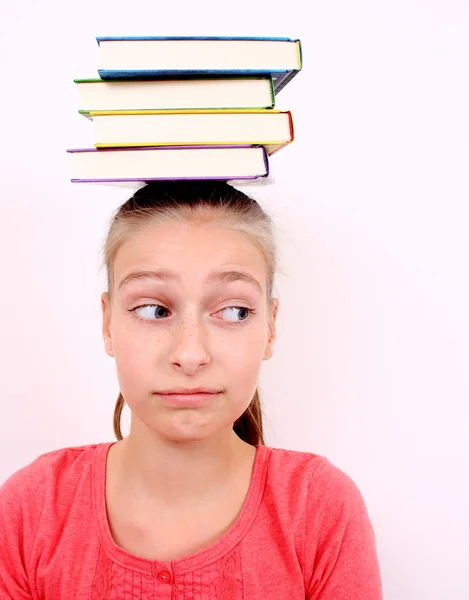 Озадаченная девушка с книгами на голове — стоковое фото