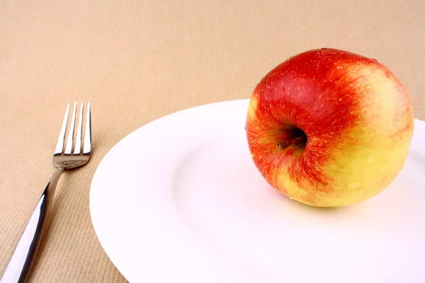 Manzana roja en plato blanco y tenedor —  Fotos de Stock