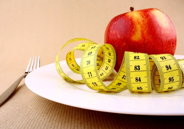 Red apple on white plate with tape measure, knife and fork — Stock Photo, Image