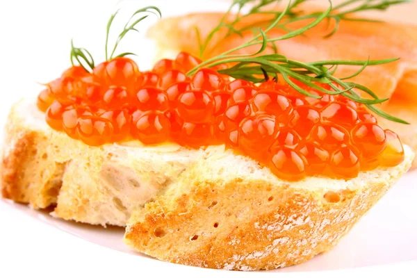 Красная икра на хлебе на белой тарелке крупным планом — стоковое фото
