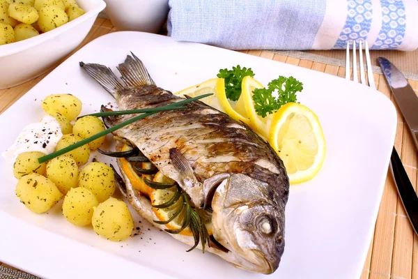 Pesce alla griglia servito con patate, salsa e limone — Foto Stock