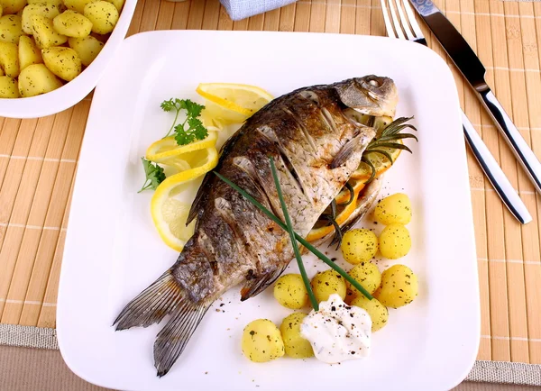 Peixe grelhado com batatas, molho e limão — Fotografia de Stock