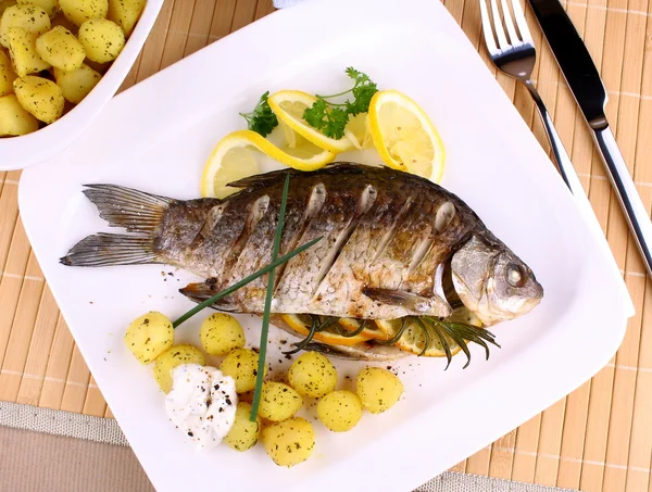 Poisson grillé servi avec pommes de terre, citron et sauce — Photo