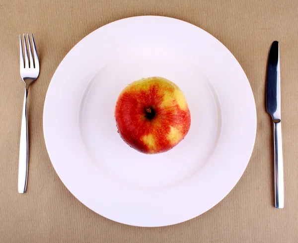 Healthy food - apple on a white plate with fork and knife — Stock Photo, Image
