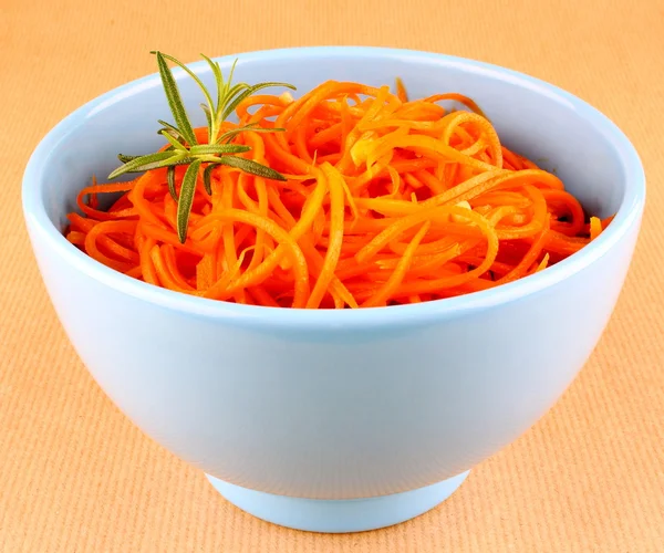 Salada de cenoura quente em tigela azul no fundo marrom — Fotografia de Stock