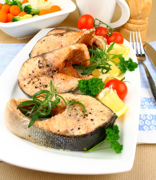 Four Grilled salmon steak with vegetables on white plate — 图库照片