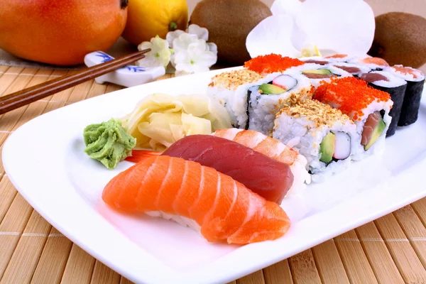 Appetizing sushi with wasabi, fruits and chopsticks — Stock Photo, Image