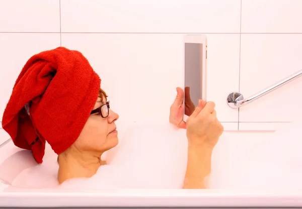 Reife Frau in Badewanne mit Tablet-Computer — Stockfoto