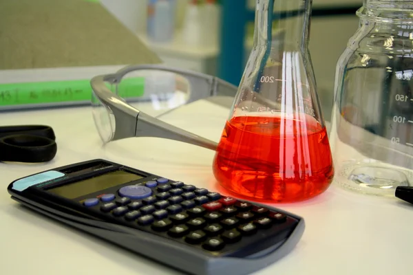 Rode vloeistof in het bekerglas op de tafel in het laboratorium — Stockfoto