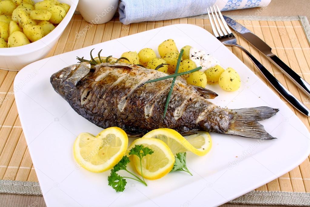 Grilled fish with potatoes, sauce, lemon and cutlery