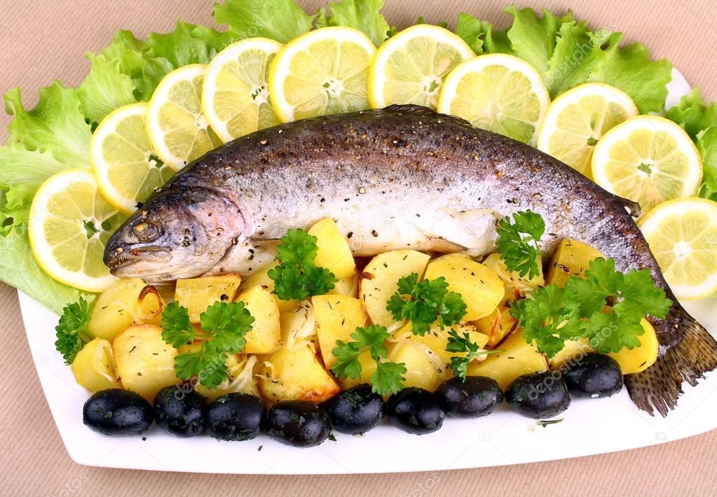 Baked trout with potatoes, black olives, lemon and salad