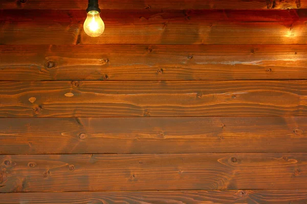 Old wooden board with bulb as background — Stock Photo, Image