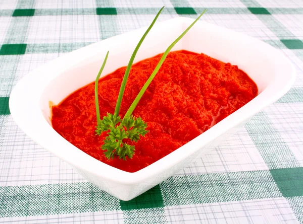 Ajvar rojo brillante en tazón blanco con cebollino y perejil — Foto de Stock