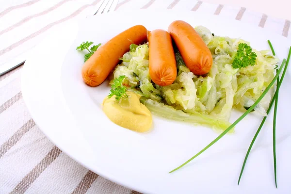 Mini wieners on fried cabbage with mustard and chives — Stock Photo, Image