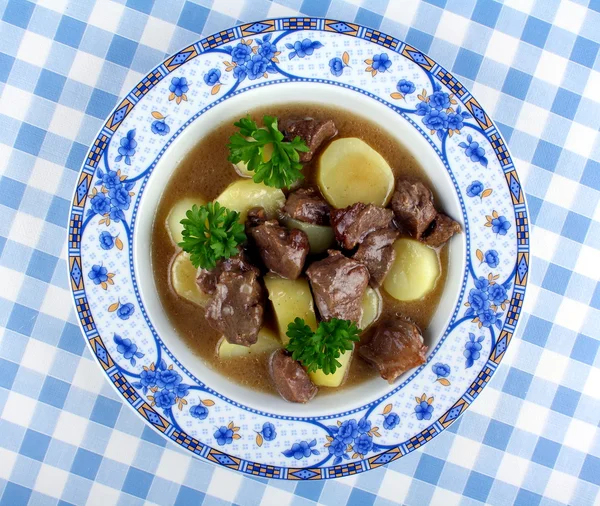 Wild goulash with potato, sauce on blue plate — Stock Photo, Image